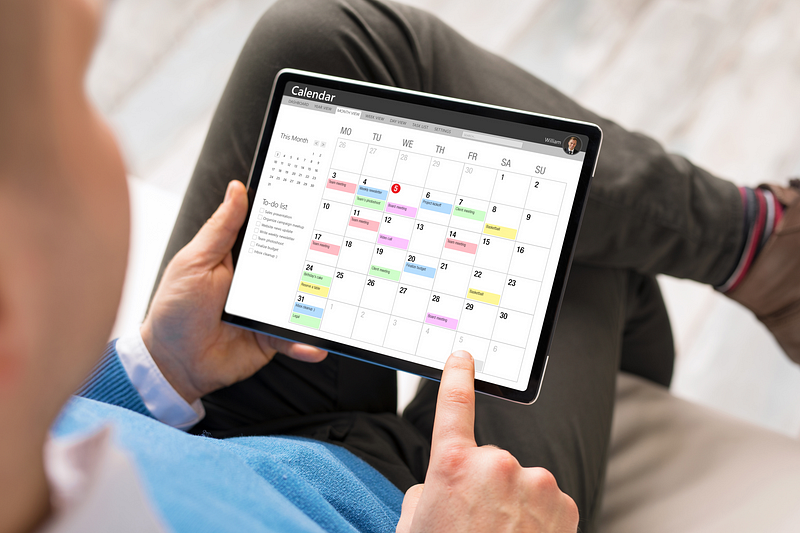 Person managing ABA clinic schedule using a digital calendar on a tablet.