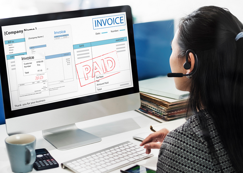 Clinic billing staff reviewing paid invoices on a desktop screen as part of ABA revenue cycle management.
