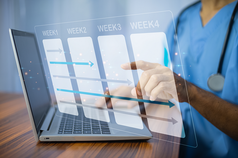 Clinician using ABA clinic management software to view weekly scheduling and progress tracking on a laptop.
