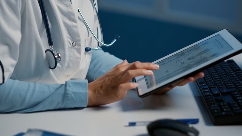 Healthcare professional reviewing client scheduling details on a tablet for ABA practice management.