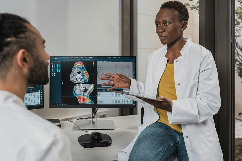 Behavior analyst discussing patient data with colleague in front of clinical workflow software monitors