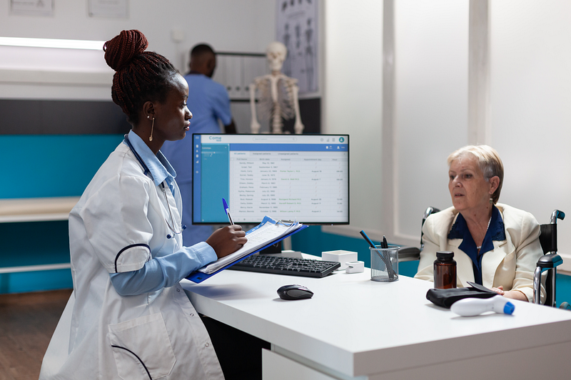 Healthcare provider using an ABA practice management system while meeting with a client in a modern clinic.