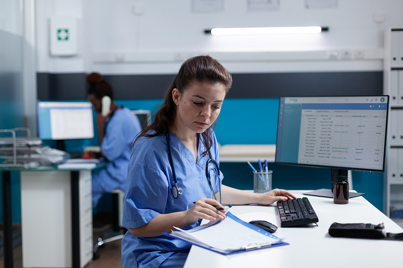 Healthcare professional managing credential compliance and clinical scheduling on a computer in an ABA clinic.