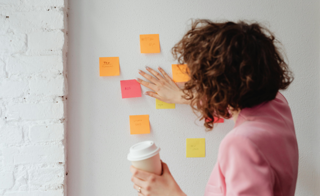 Person organizing sticky notes on wall for structured routines in parent training in ABA