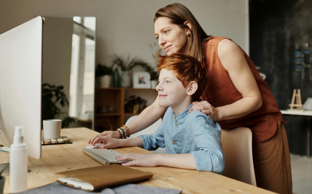 Parent guiding child at computer for support for children with autism at home