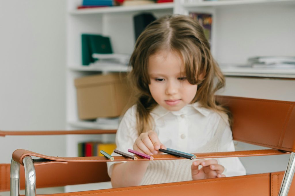 Child with autism lining up pencils on a chair, showing focus and routine as children with autism handle school activities