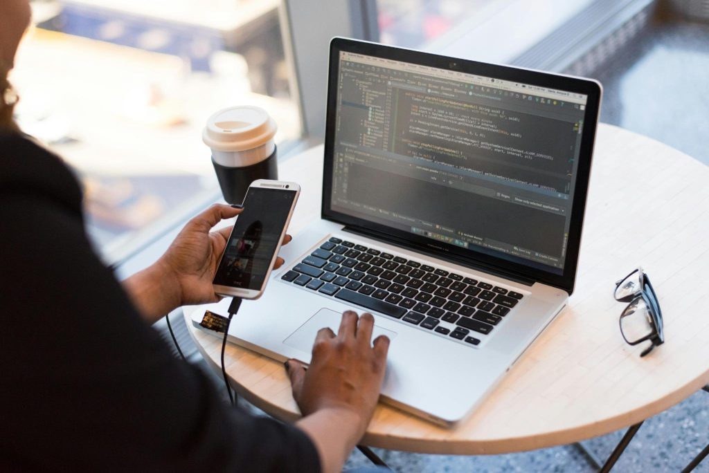 Developer using phone and laptop to build ABA Artificial Intelligence tools for autism therapy support
