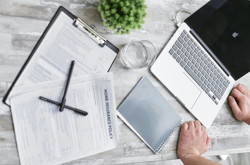 Insurance paperwork and laptop on a desk representing the ABA authorization process and administrative approvals.